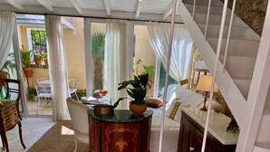 A room with a staircase, a dining area with a table and chairs, and a view of the outside. - The Little Patio House (Corfu)