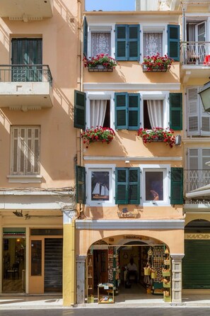A multi-story building with balconies, flower boxes, and a shop at the ground level.