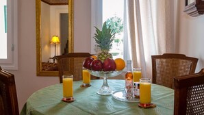 Una mesa de comedor con un frutero, vasos de jugo de naranja y una vela.