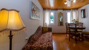 Una habitación acogedora con techo de madera, un sofá estampado, una mesa de comedor con sillas y una lámpara.