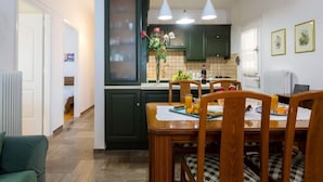 A modern kitchen with dark green cabinets, a wooden dining table, and pendant lights. - Pausa Verde - Recently renovated apt, private parking (Corfu)