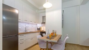 Een moderne keuken met witte kasten, een roestvrijstalen koelkast en een eettafel met stoelen.