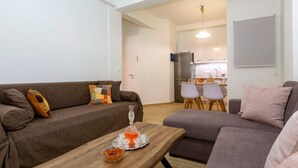 Een woonkamer met een bank, een salontafel en een keuken op de achtergrond.
