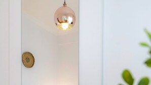 Et soveværelse med seng, sengebord, lampe og en plante i forgrunden.