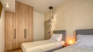 Ein modernes Schlafzimmer mit zwei Betten, einem Holzschrank und einem Nachttisch mit einer Lampe.