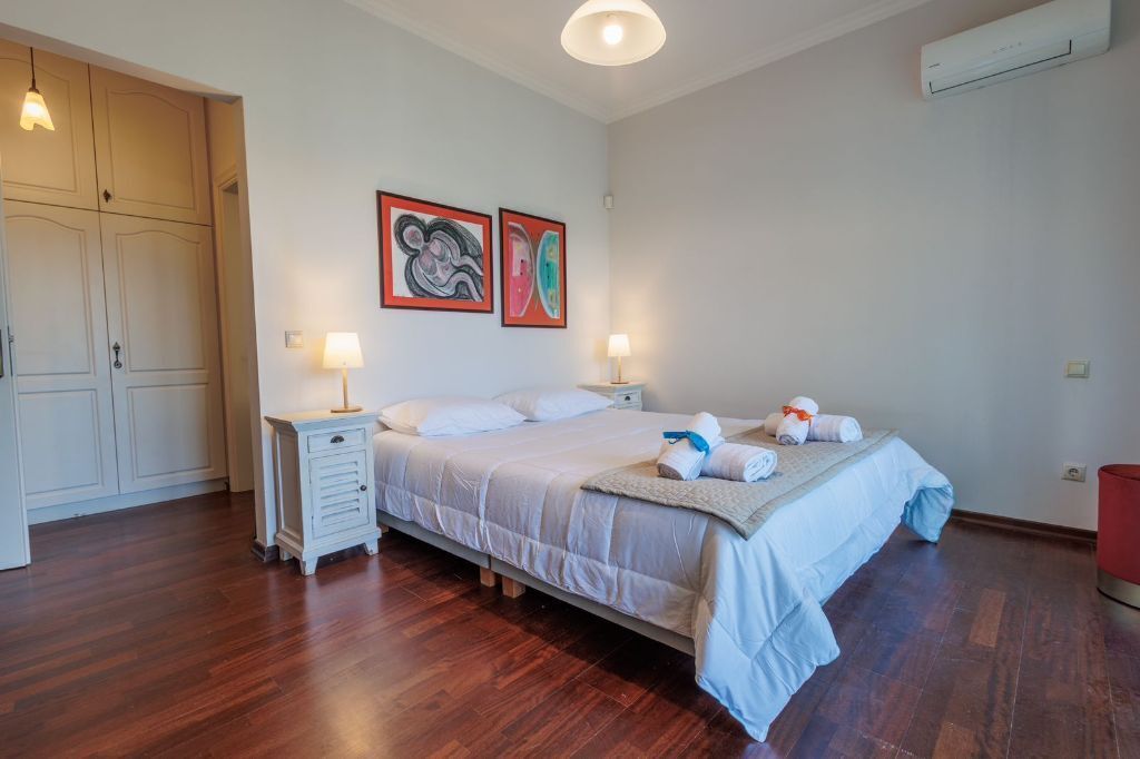 A bedroom with a bed, bedside tables, a wardrobe, and two wall-mounted artworks.