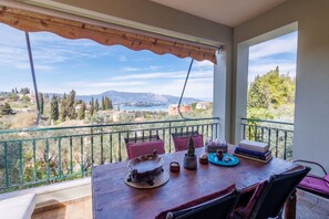 Ein Balkon mit Blick auf eine gebirgige Landschaft, ein Holztisch mit einer dekorativen Schale und einige Bücher.