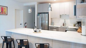 A modern kitchen with a central island, stainless steel appliances, and bar stools. - Revytalize - Cozy 3 Bedroom Condo (Revelstoke)