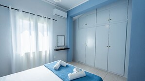 Ein Schlafzimmer mit einem Bett, einem Kleiderschrank, einem Spiegel und einem Regal mit Handtüchern.