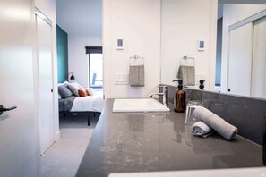 Une salle de bain moderne avec un grand miroir, un lavabo blanc et un porte-serviettes.