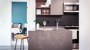 A modern kitchen with a marble island, stainless steel appliances, and a wooden shelf with decorative items. - The Three Bear Penthouse - with Hot Tub (Revelstoke)