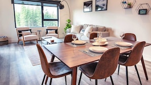 A modern dining area with a wooden table set for six, surrounded by chairs. - The Three Bear Penthouse - with Hot Tub (Revelstoke)