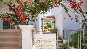 Een bordje voor 'Antonia's Apartments Studios' met een witte achtergrond en gouden letters.