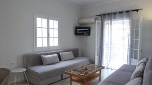 A modern living room with a grey sofa, a wooden coffee table, and a flat-screen TV mounted on the wall. - Antonias Iris apartment (Corfu)