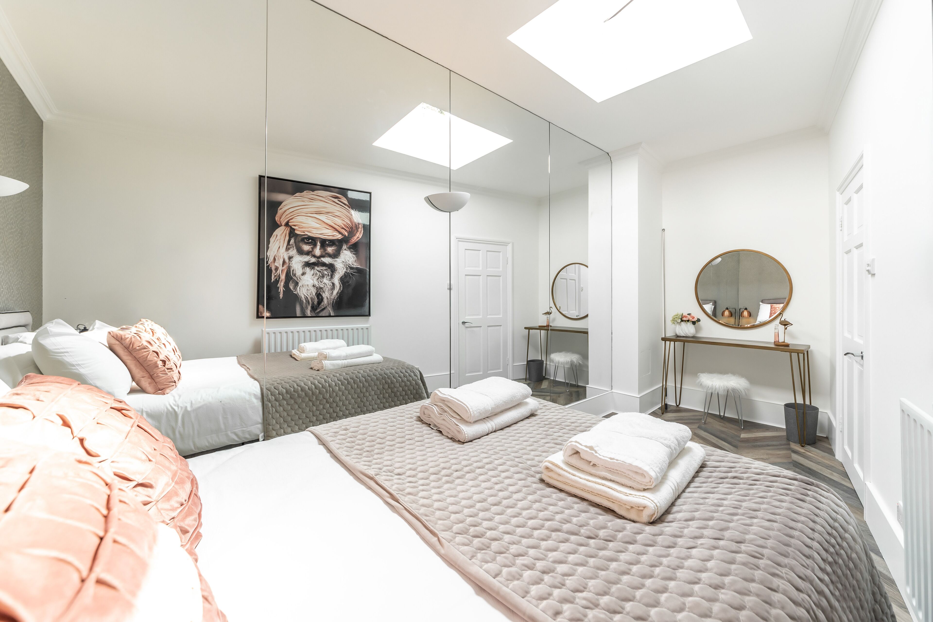 A modern bedroom with a large bed, a bedside table, a mirror, and a framed picture on the wall.