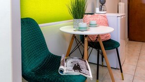 A small, cozy room with a green chair, a small table with a plant, a pink cushion, and a coffee machine. - Theodora's Nest - air coditioning, located in the heart of Corfu old city (Corfu)