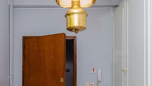 A room with a wooden door, a white radiator, a light switch, and a telephone on the wall. - Theodora's Nest - air coditioning, located in the heart of Corfu old city (Corfu)