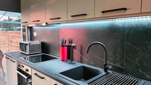 Uma cozinha compacta com micro-ondas, chaleira vermelha e pia.