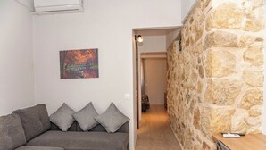 Un salon moderne avec un canapé gris, une table basse en bois et un mur en pierre.
