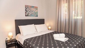 Un lit bien fait, recouvert d’une couvre-lit à motifs étoilés, avec deux lampes de chevet et un tableau accroché au mur.