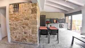 Uma cozinha moderna com detalhes em pedra, uma sala de jantar com mesa e cadeiras, e um ventilador de teto.