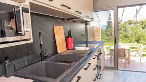 Cozinha moderna com forno embutido, uma pia grande e porta deslizante para um pátio externo.