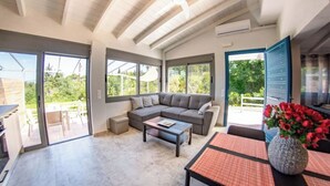 Uma sala de estar espaçosa com um amplo sofá modular, uma mesa de centro e um espaço de refeições com mesa e cadeiras.