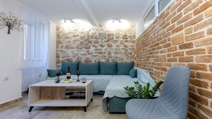 A cozy room with a stone wall, a blue sofa, a wooden coffee table, and a grey armchair. - Volto Achilles Suite (Corfu)