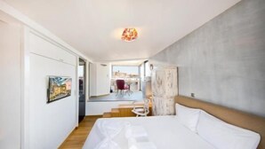 Een hotelkamer met een bed, een bureau en een stoel. Er is een trap die naar een buitenruimte leidt.