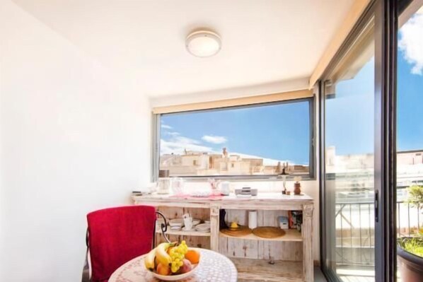 A balcony with a view of buildings, a small table with a bowl of fruit, and a red towel. - Topfloor stylish apartment with Acropolis view! (Athens)