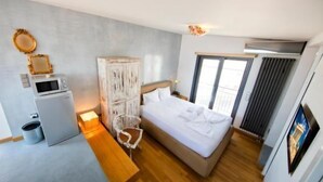 Een moderne hotelkamer met een bed, een kleine kitchenette, een zithoek en een groot raam.