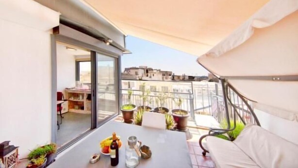 Een balkon met een tafel, plantenbakken en een bank.