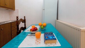 A small kitchen with a table set for breakfast, including a book, fruit, and a glass of orange juice. - Campiello Blue Studio - Central cozy studio with garden in Corfu old town (Corfu)