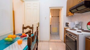 A compact kitchen with a dining area, a microwave, a stove, and a small window. - Campiello Blue Studio - Central cozy studio with garden in Corfu old town (Corfu)