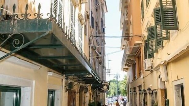 A narrow street with buildings on either side, a scooter parked on the right, and a person walking in the distance. - Conte Studio - located in the heart of Corfu Old town (Kerkira)