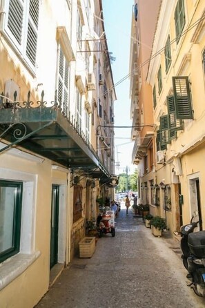 A narrow street with buildings on either side, a scooter parked on the right, and a person walking in the distance. - Conte Studio - located in the heart of Corfu Old town (Kerkira)
