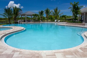 Relax by the resort pool surrounded by lush greenery and palm trees.