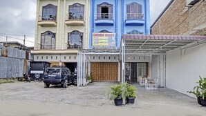 Un edificio con un letrero que dice 'Orien Kost' y una entrada cubierta con sillas y plantas en macetas.