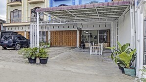 Un edificio con entrada techada, plantas en macetas y un coche estacionado.
