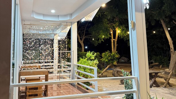 An outdoor patio area with a wooden bench, a railing, and potted plants. - Rang Noknoy Resort at Koh Larn (Koh Lan)