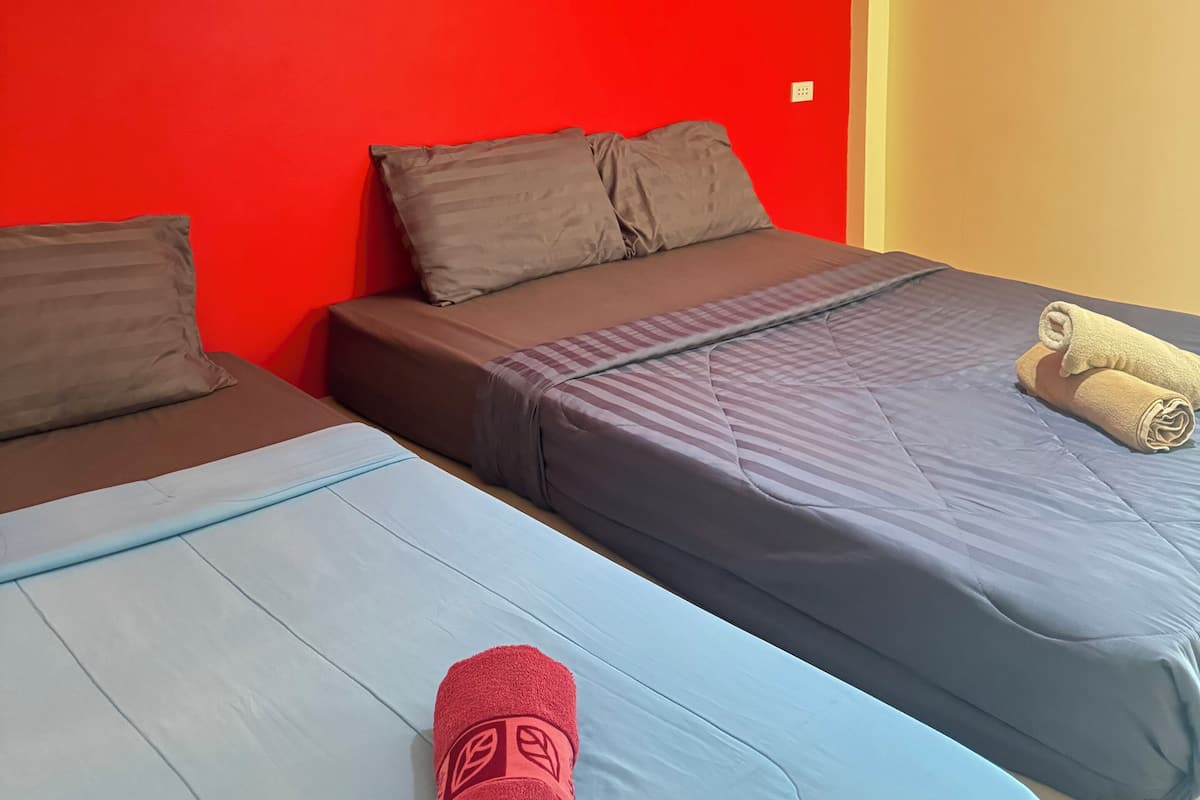 Quarto com duas camas, cada uma com um cobre-cama de cor diferente.