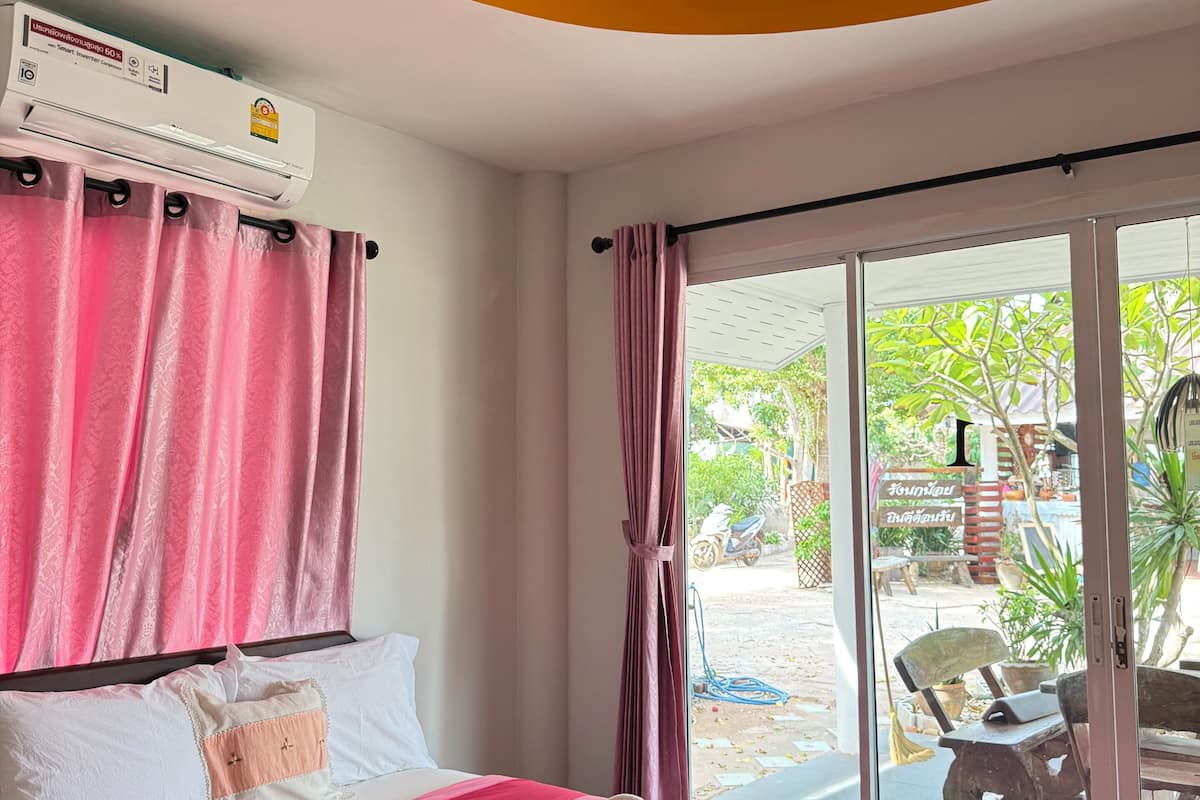 Quarto de hotel com cama, cortinas cor-de-rosa, design de estrelas no teto e ar condicionado.