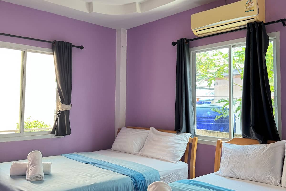Quarto de hotel com duas camas, janela com cortinas, aparelho de ar condicionado e luminária no teto.