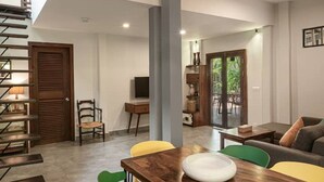 Een moderne woonkamer met een trap, een eethoek met een houten tafel en een bank.