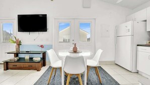 Una cocina moderna con armarios blancos, un refrigerador y un comedor con una mesa redonda y sillas blancas.