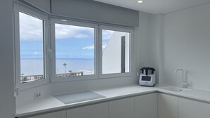 A modern kitchen with a large window offering a view of the sea and a balcony. - Tamara Alto (Acantilados de Los Gigantes)