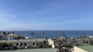 A coastal residential area with buildings, palm trees, and a view of the sea. - Tamara Alto (Acantilados de Los Gigantes)