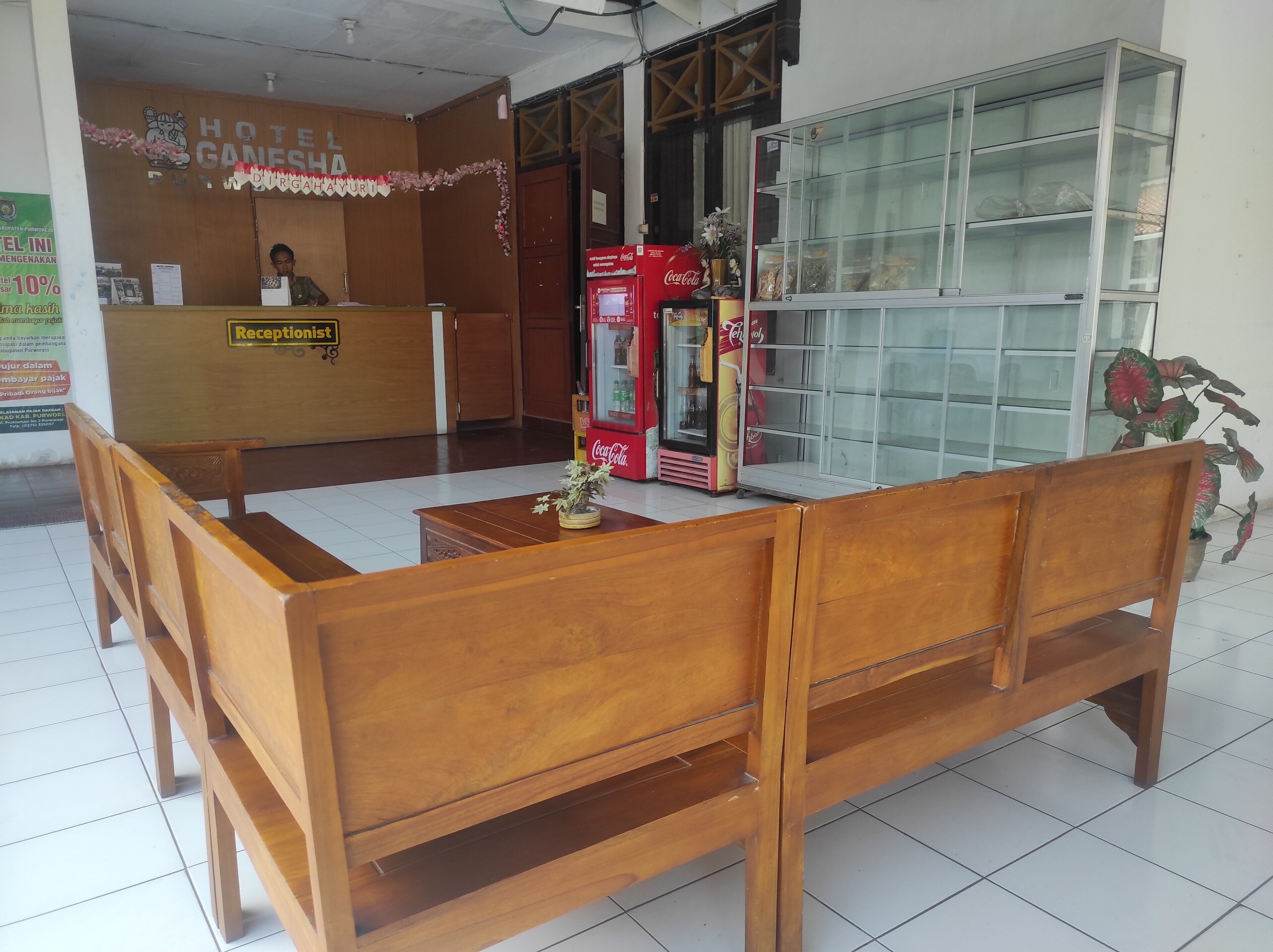 Un espace d’accueil avec des meubles en bois, un réfrigérateur Coca-Cola et un comptoir de réception.