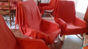 A room with three red-covered chairs, a wooden table, and a staircase in the background. - Gite Coriosolites (Quemper-Guézennec)