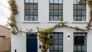 A modern two-story building with a white facade, black-framed windows, and a blue door.